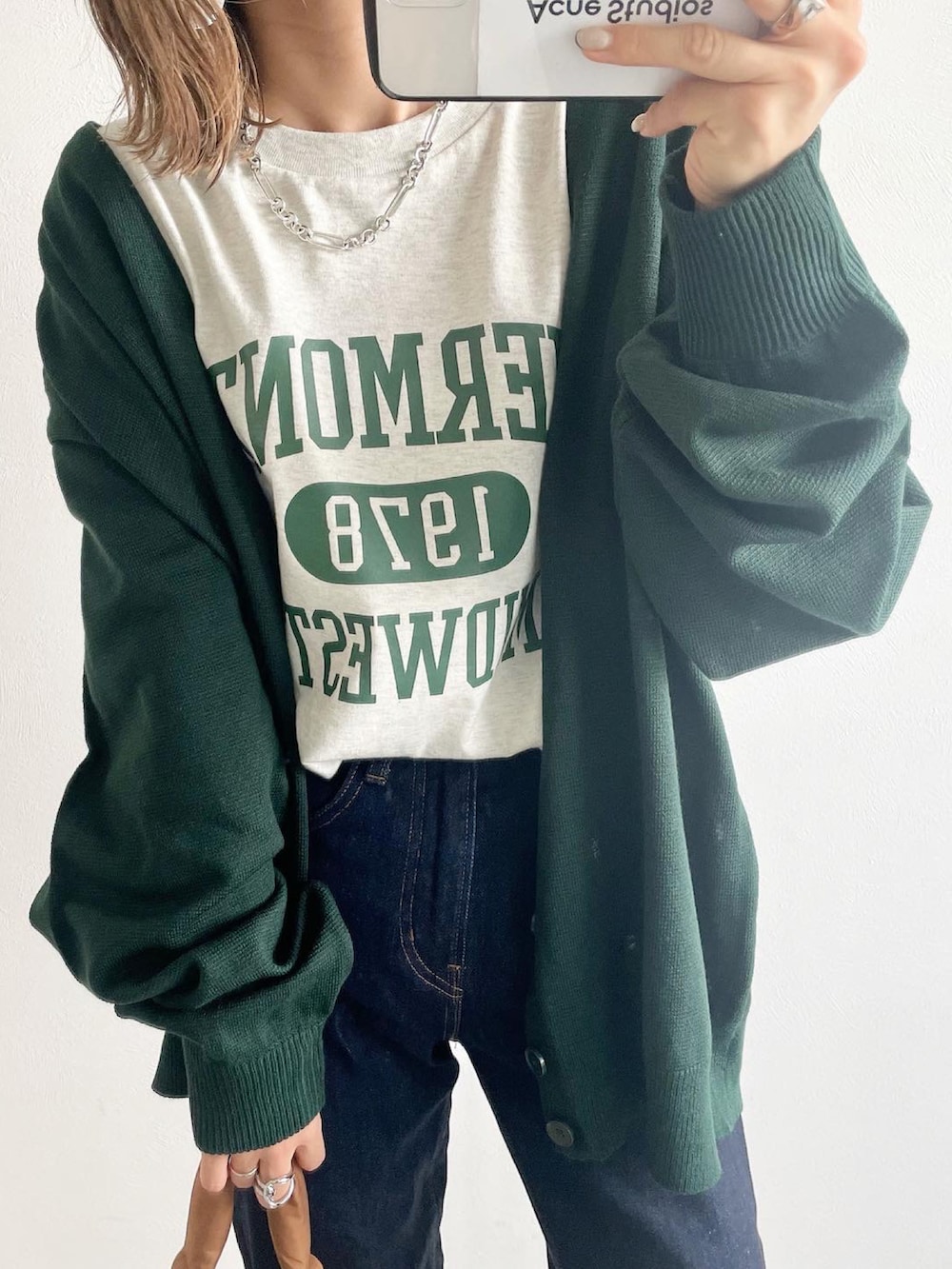 グリーン系のカーディガン/ボレロ、ホワイト系のTシャツ/カットソー、ブルー系のデニムパンツを着用したレディースの秋コーディネートの3枚目の写真