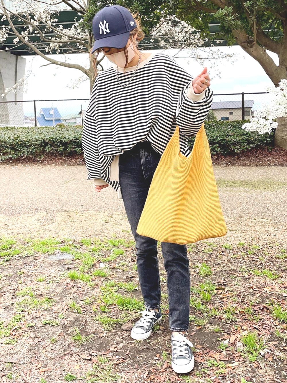 ブラック系のTシャツ/カットソー、イエロー系のトートバッグ、ブラック系のデニムパンツを着用したレディースの春コーディネートの2枚目の写真