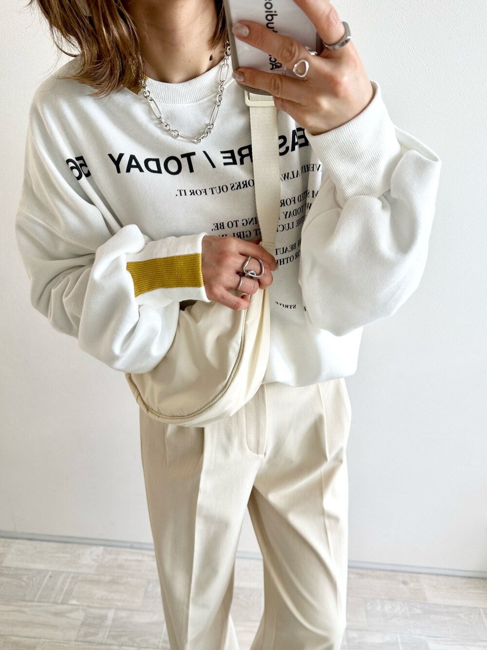 ブルー系のデニムパンツ、オレンジ系のスカート、ホワイト系のスウェットを着用したレディースの春コーディネートの2枚目の写真