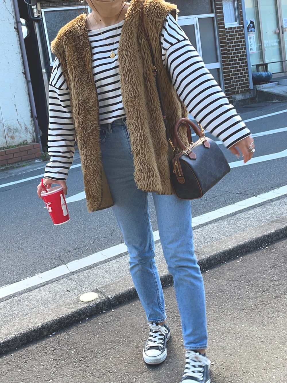ホワイト系のTシャツ/カットソー、ブルー系のデニムパンツ、ブラウン系のベストを着用したレディースの春コーディネートの5枚目の写真