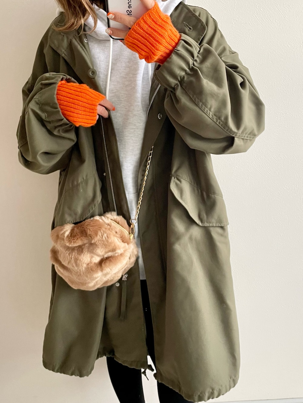オレンジ系のスニーカー、ベージュ系のショルダーバッグ、グリーン系のモッズコートを着用したレディースの冬コーディネートの2枚目の写真