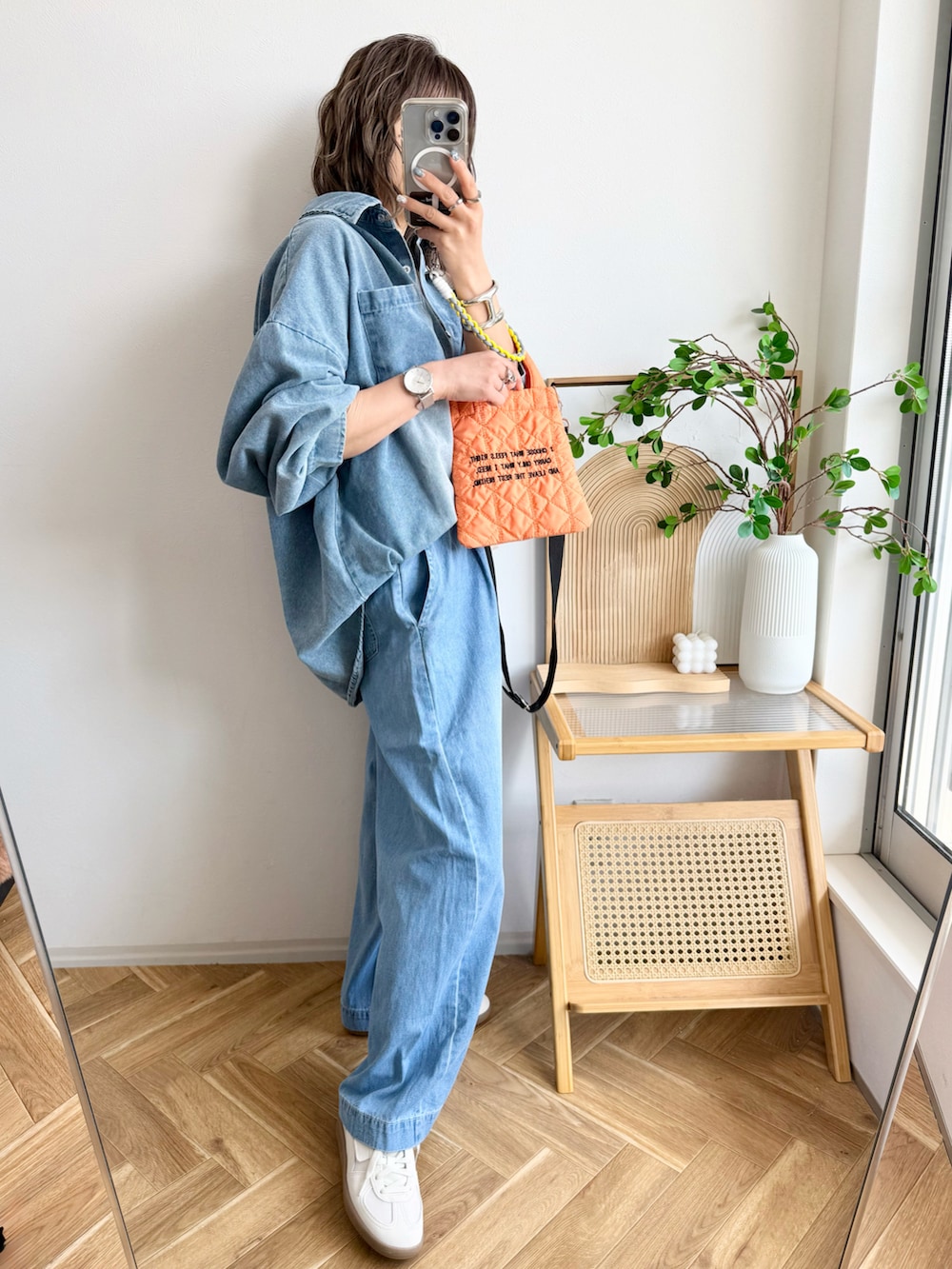 ブルー系のデニムパンツ、オレンジ系のショルダーバッグ、ホワイト系のスニーカーを着用したレディースの春コーディネートの2枚目の写真