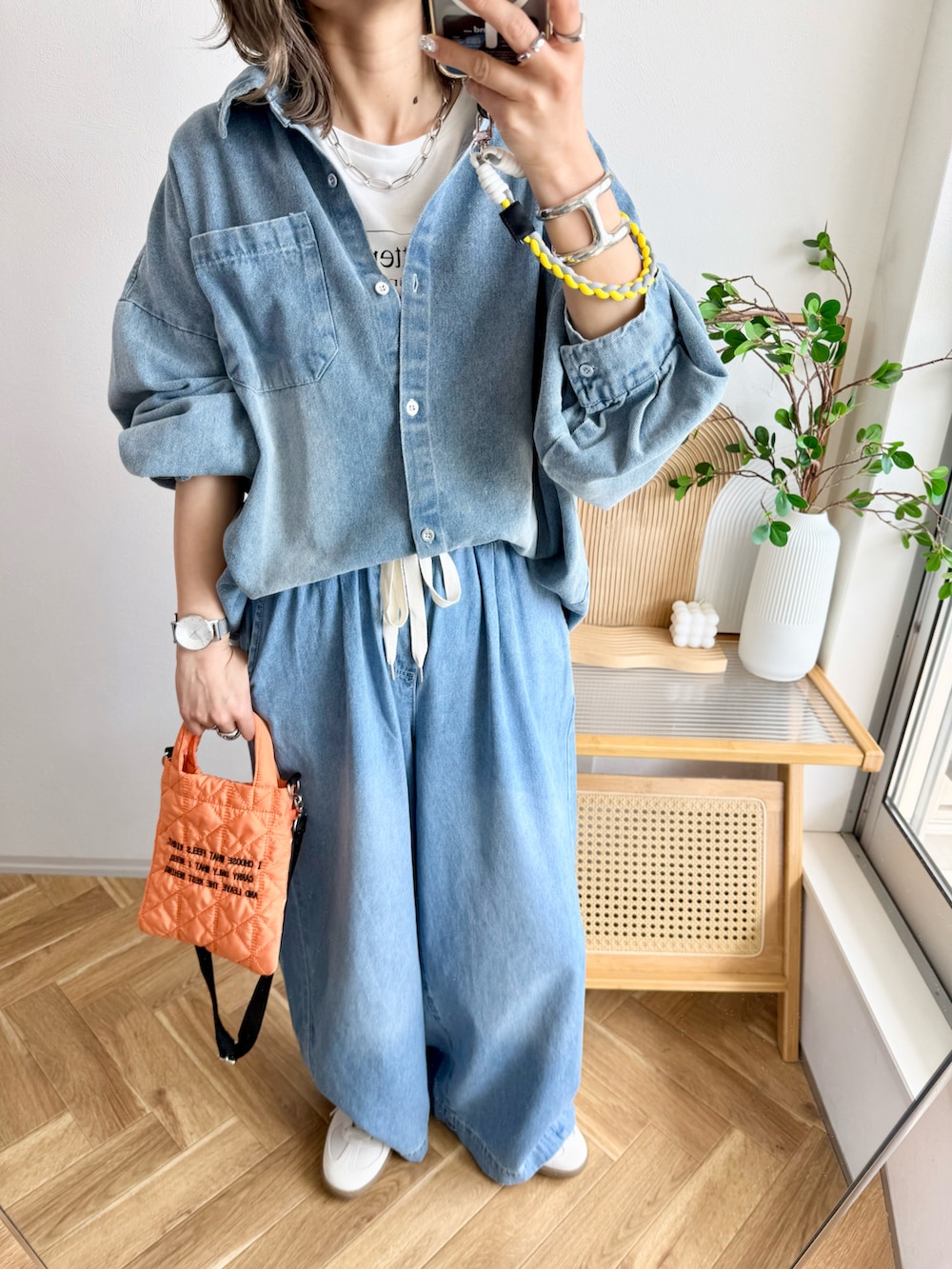 ブルー系のデニムパンツ、オレンジ系のショルダーバッグ、ホワイト系のスニーカーを着用したレディースの春コーディネートの3枚目の写真