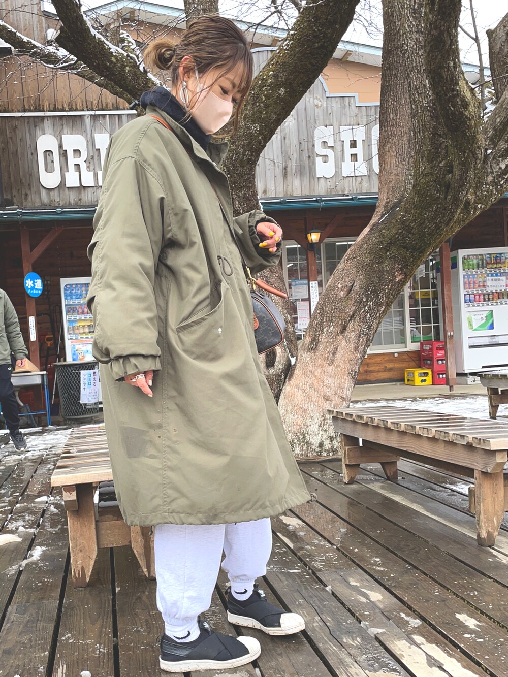 ブラック系のスニーカー、グリーン系のモッズコート、ホワイト系のスウェットパンツを着用したレディースの春コーディネートの3枚目の写真