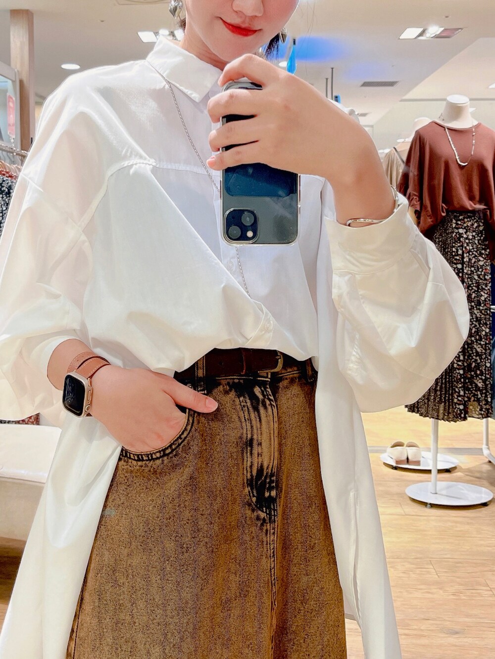 ホワイト系のチュニック、ブラウン系のスカート、ブラック系のブーツを着用したレディースの秋コーディネートの4枚目の写真