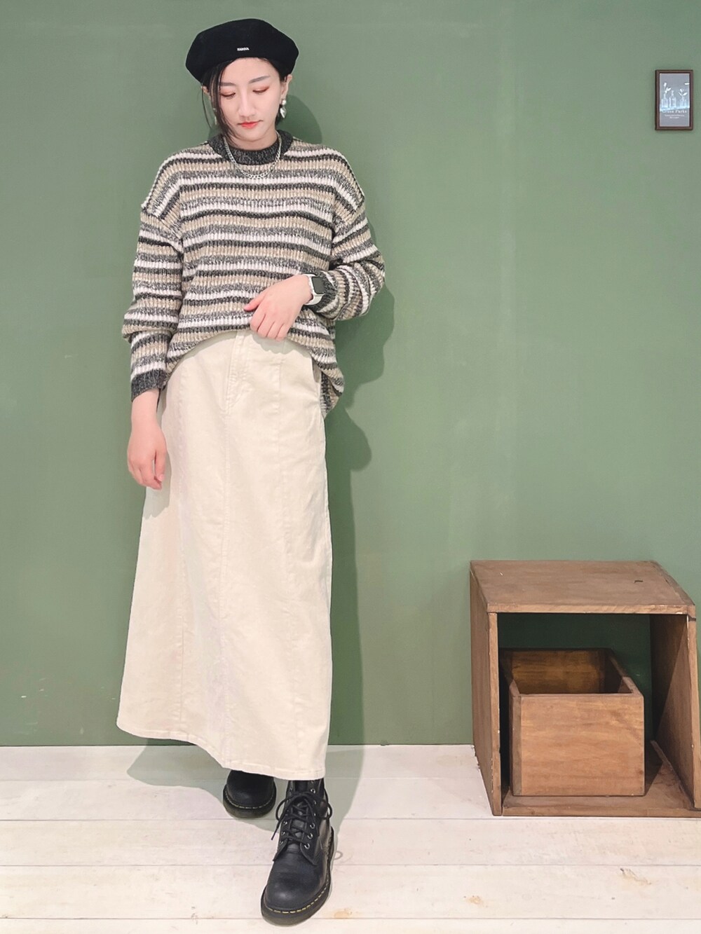 グレー系のニット/セーター、ベージュ系のスカート、ブラック系のハンチング/ベレー帽を着用したレディースの冬コーディネートの2枚目の写真