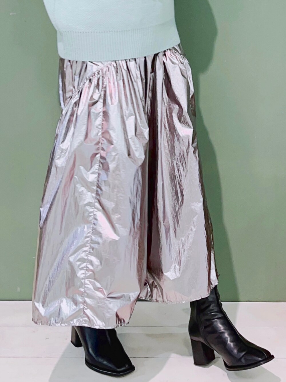 グリーン系のニット/セーター、シルバー系のスカート、ブラック系のブーツを着用したレディースの冬コーディネートの2枚目の写真