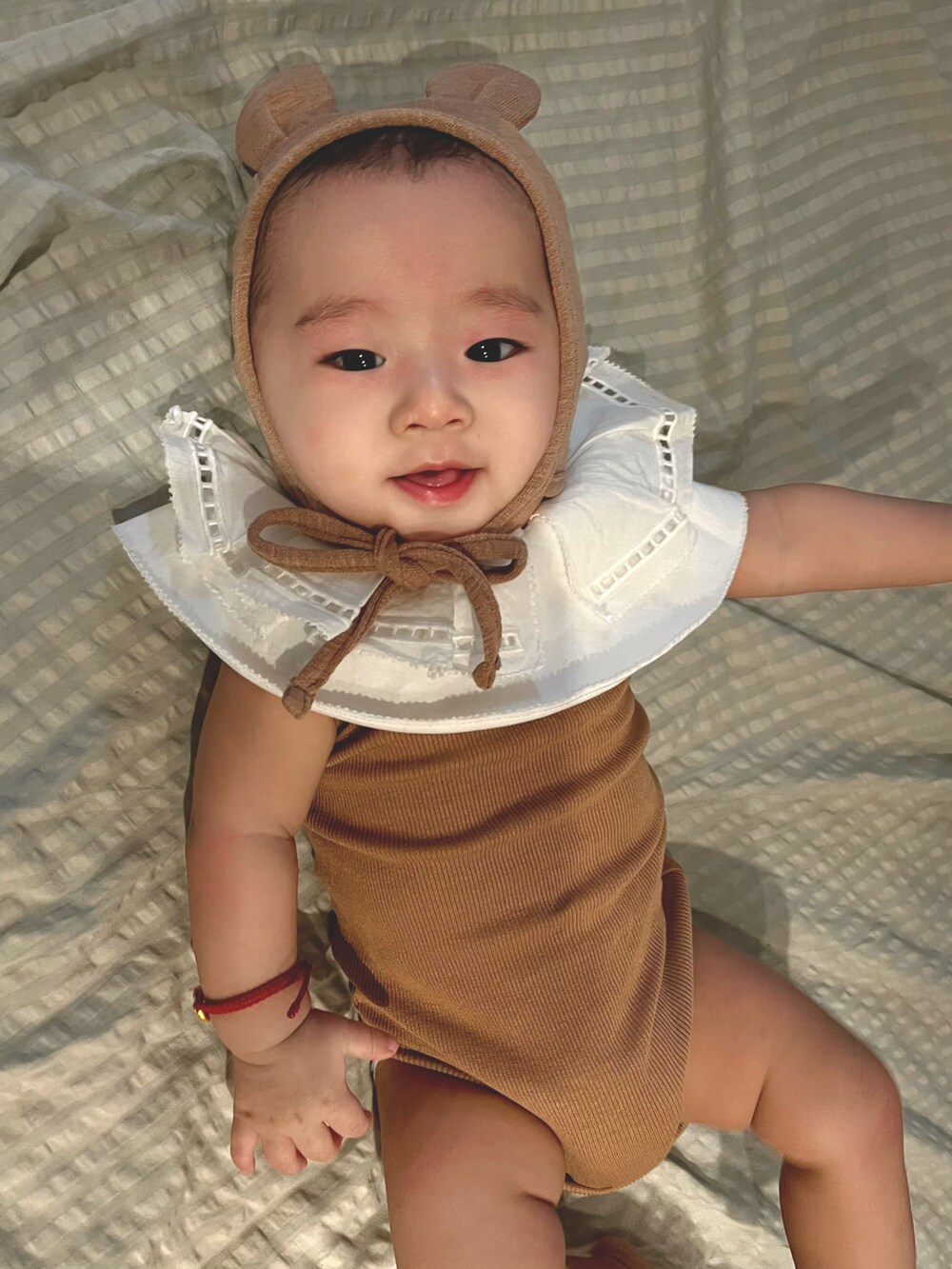 ブラウン系のその他ベビーウェア、ブラウン系のベビーパジャマ/スリーパー、ホワイト系のスタイ/よだれかけを着用したキッズの春コーディネートの2枚目の写真