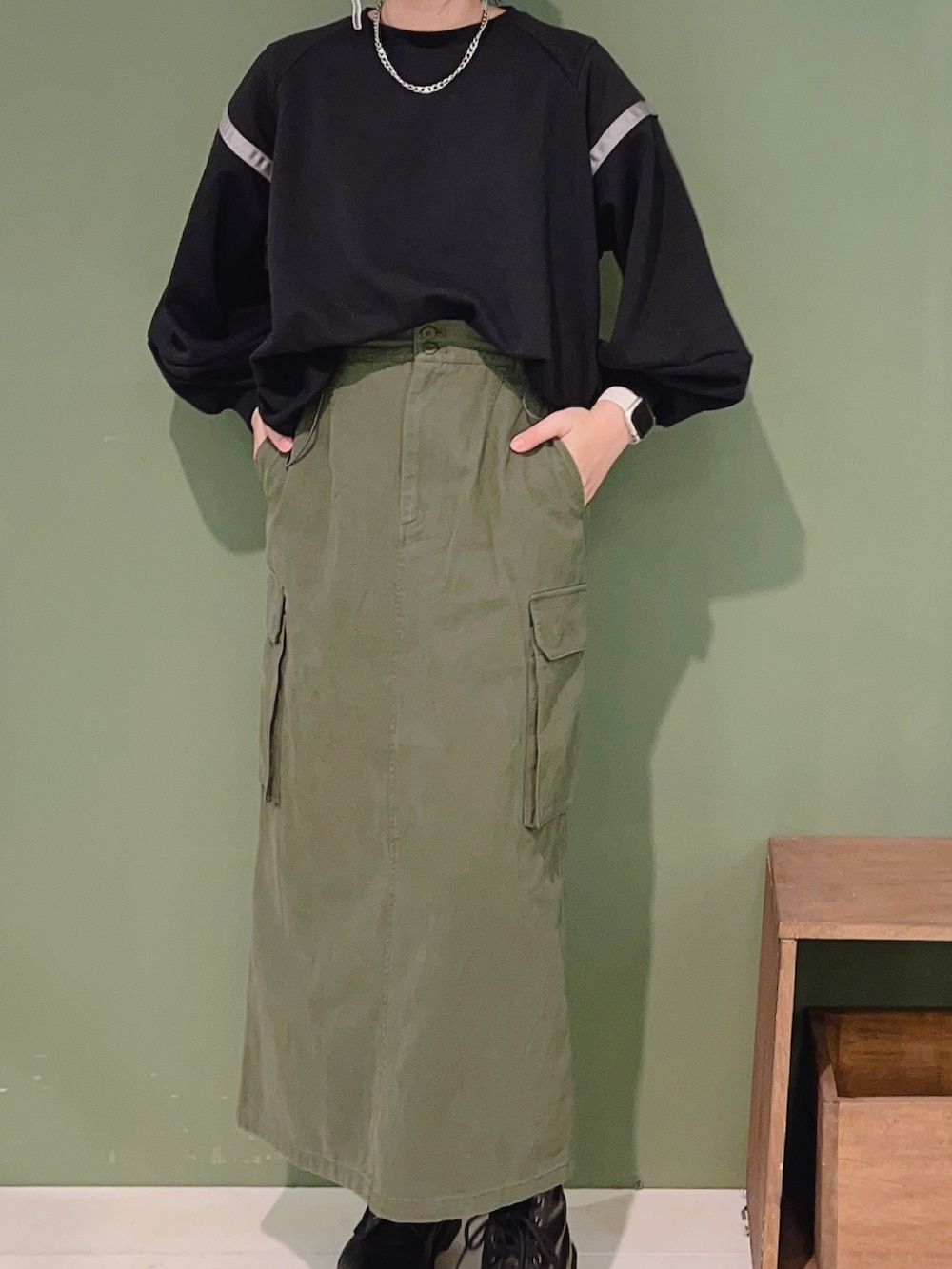 ブラック系のTシャツ/カットソー、グリーン系のスカート、ブラック系のブーツを着用したレディースの冬コーディネートの2枚目の写真