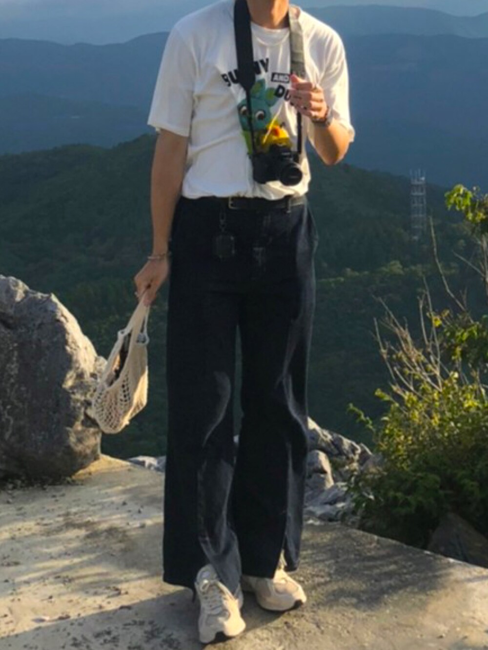 ホワイト系のTシャツ/カットソー、ベージュ系のハンドバッグ、ブルー系のデニムパンツを着用したメンズの秋コーディネートの2枚目の写真