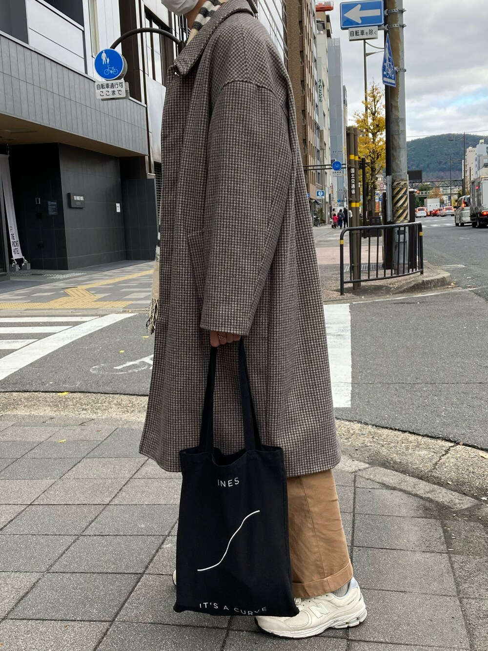 ベージュ系のチノパンツ、ベージュ系のスニーカー、ブラウン系のステンカラーコートを着用したメンズの冬コーディネートの2枚目の写真