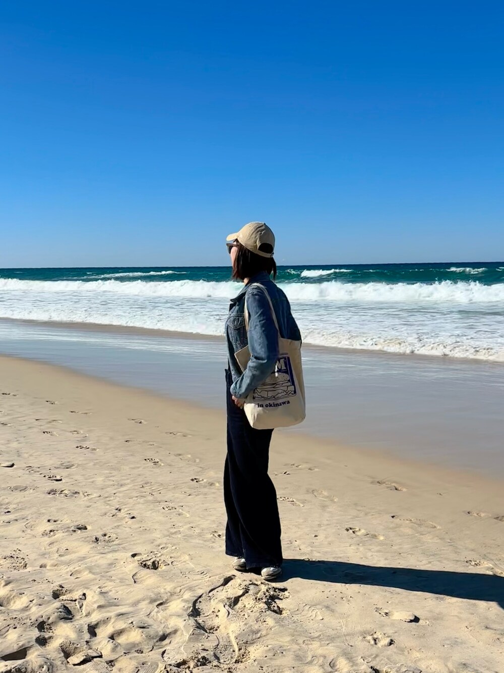 ブルー系のデニムジャケット、ホワイト系のスニーカー、ブルー系のパンツを着用したレディースの秋コーディネートの2枚目の写真