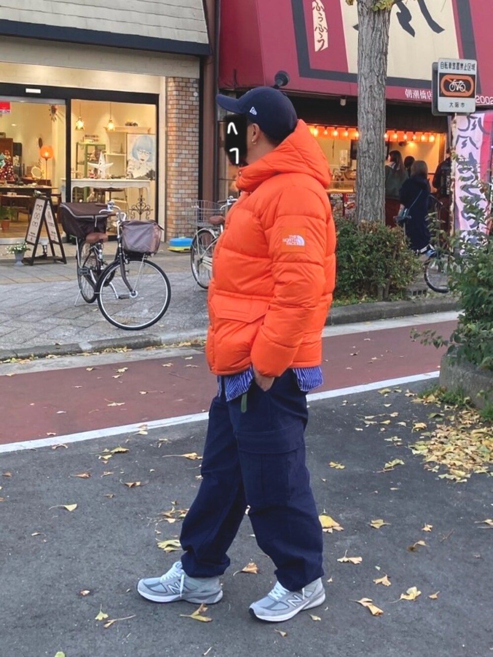 オレンジ系のダウンジャケット/コート、ブルー系のカーゴパンツ、グレー系のスニーカーを着用したメンズの冬コーディネートの2枚目の写真
