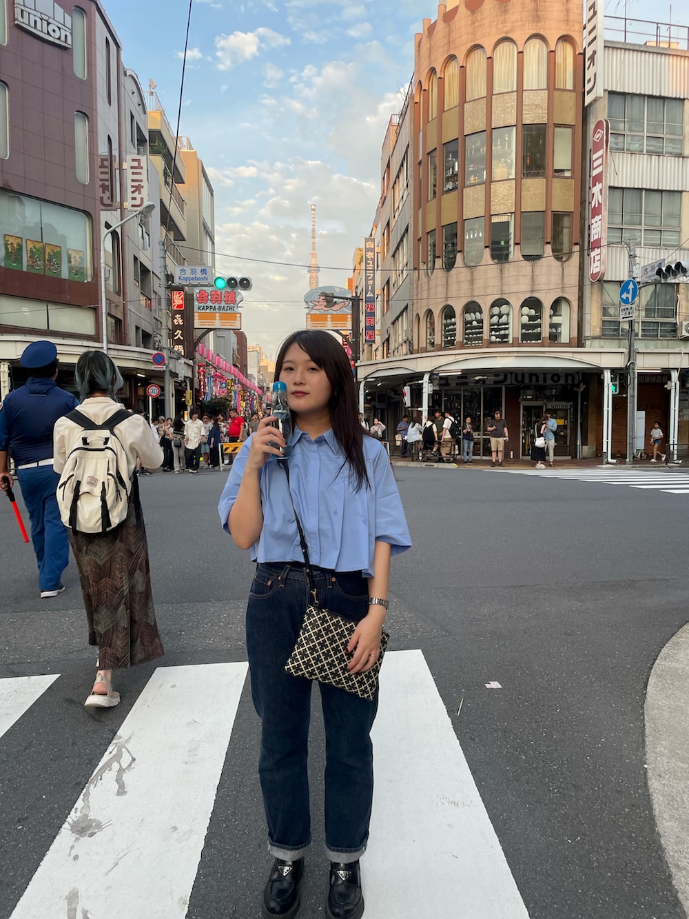 ブルー系のシャツ/ブラウス、ブラック系のバッグ、ブルー系のデニムパンツを着用したレディースの夏コーディネートの2枚目の写真