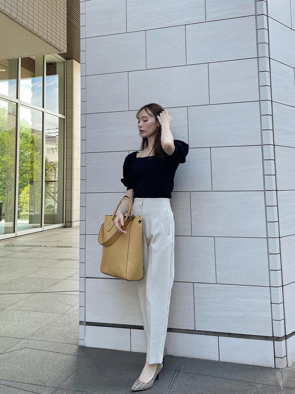 イエロー系のトートバッグ、ブラック系のトップス、ホワイト系のパンツを着用したレディースの夏コーディネートの2枚目の写真