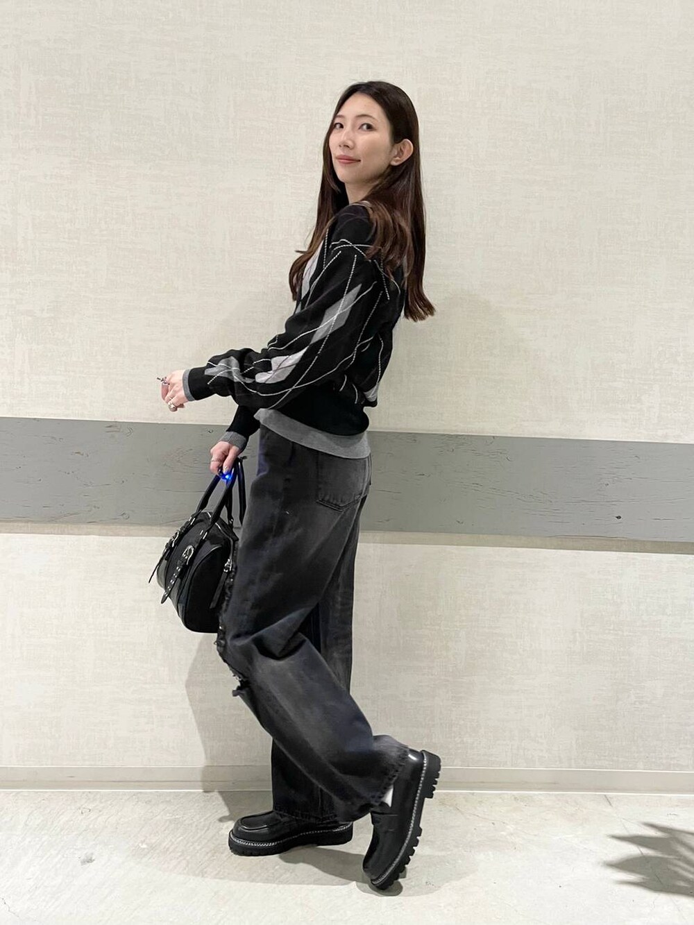 ブラック系のボストンバッグ、ブラック系のローファー、ブラック系のデニムパンツを着用したレディースの秋コーディネートの5枚目の写真