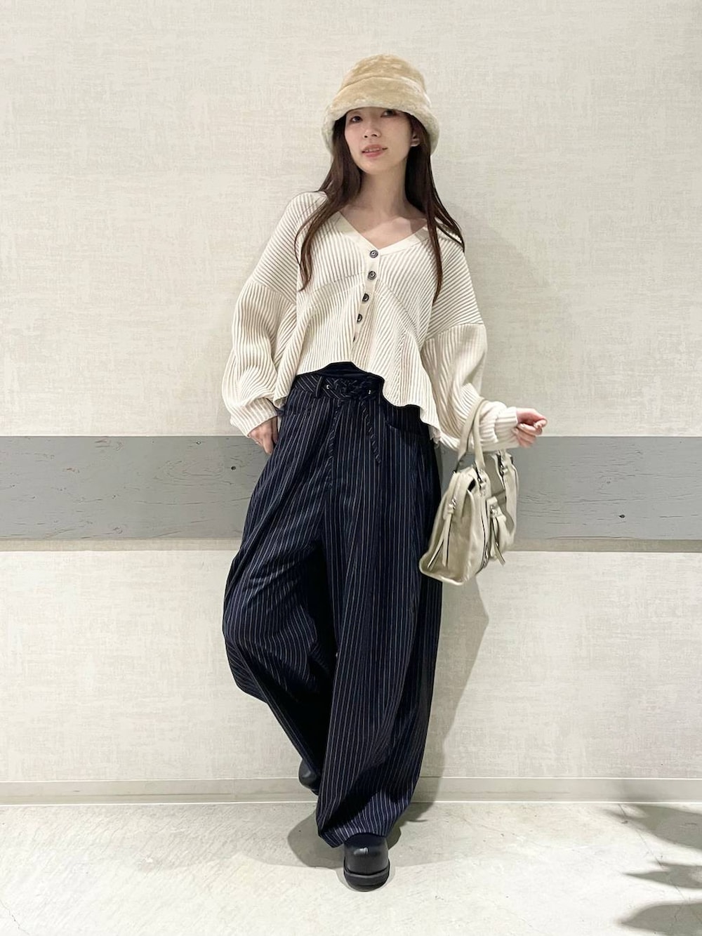 ベージュ系のボストンバッグ、ブルー系のスラックス、ブラック系のその他シューズを着用したレディースの冬コーディネートの3枚目の写真