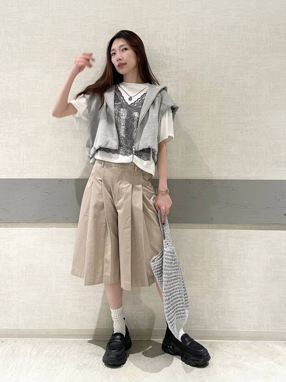 ブラック系のローファー、シルバー系のショルダーバッグ、グレー系のベストを着用したレディースの春コーディネートの2枚目の写真