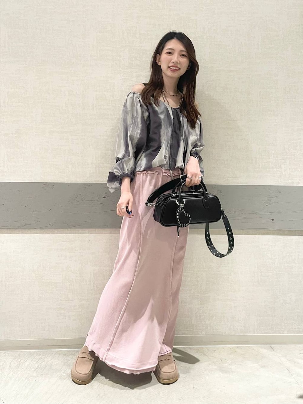 ブラック系のボストンバッグ、ベージュ系のローファー、ピンク系のスカートを着用したレディースの春コーディネートの2枚目の写真