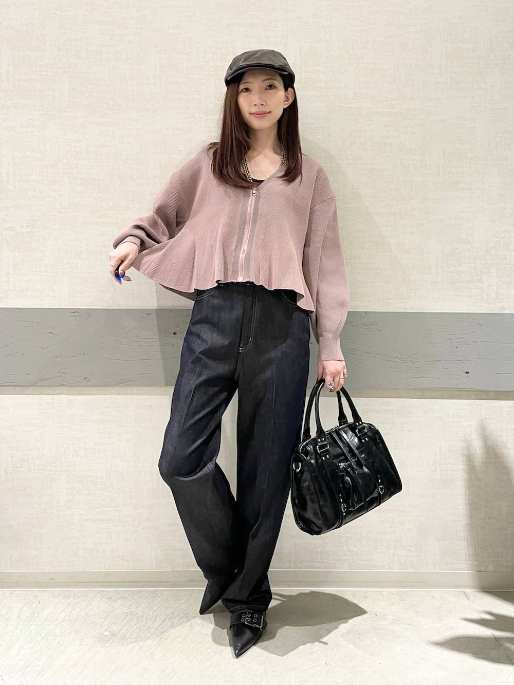 ブラック系のボストンバッグ、ブラック系のパンプス、ブルー系のデニムパンツを着用したレディースの冬コーディネートの4枚目の写真