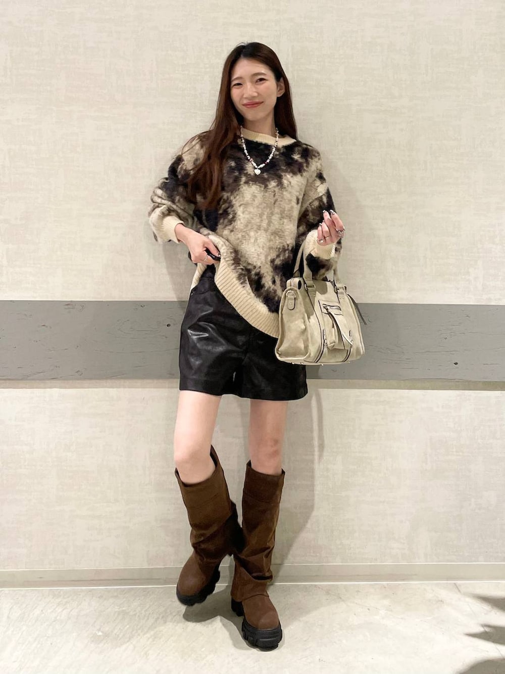 ブラウン系のニット/セーター、ベージュ系のボストンバッグ、ブラウン系のブーツを着用したレディースの秋コーディネートの2枚目の写真