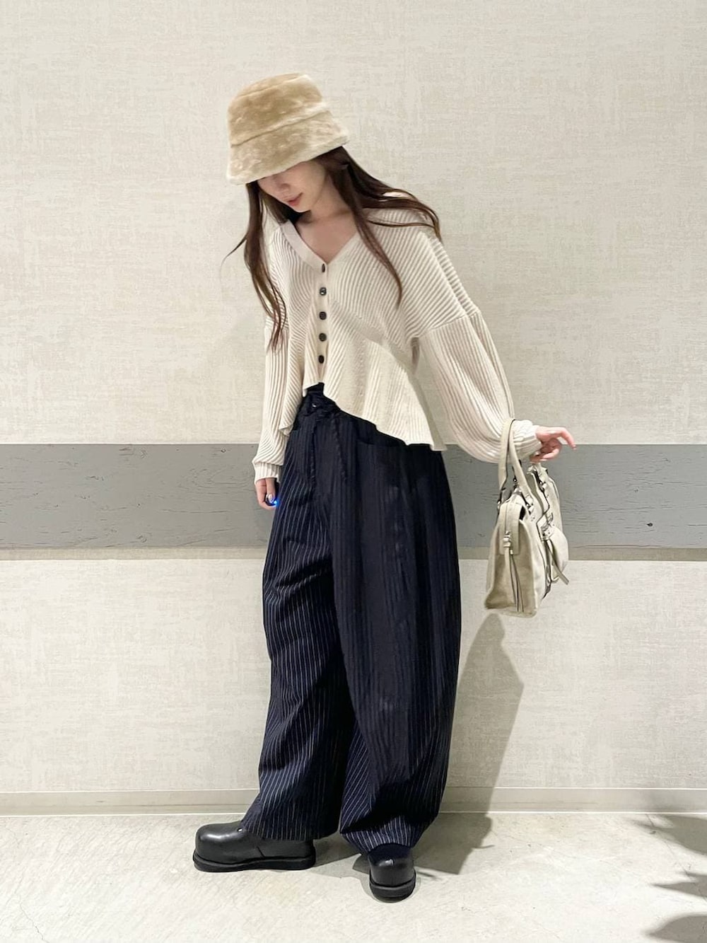 ベージュ系のボストンバッグ、ブルー系のスラックス、ブラック系のその他シューズを着用したレディースの冬コーディネートの4枚目の写真