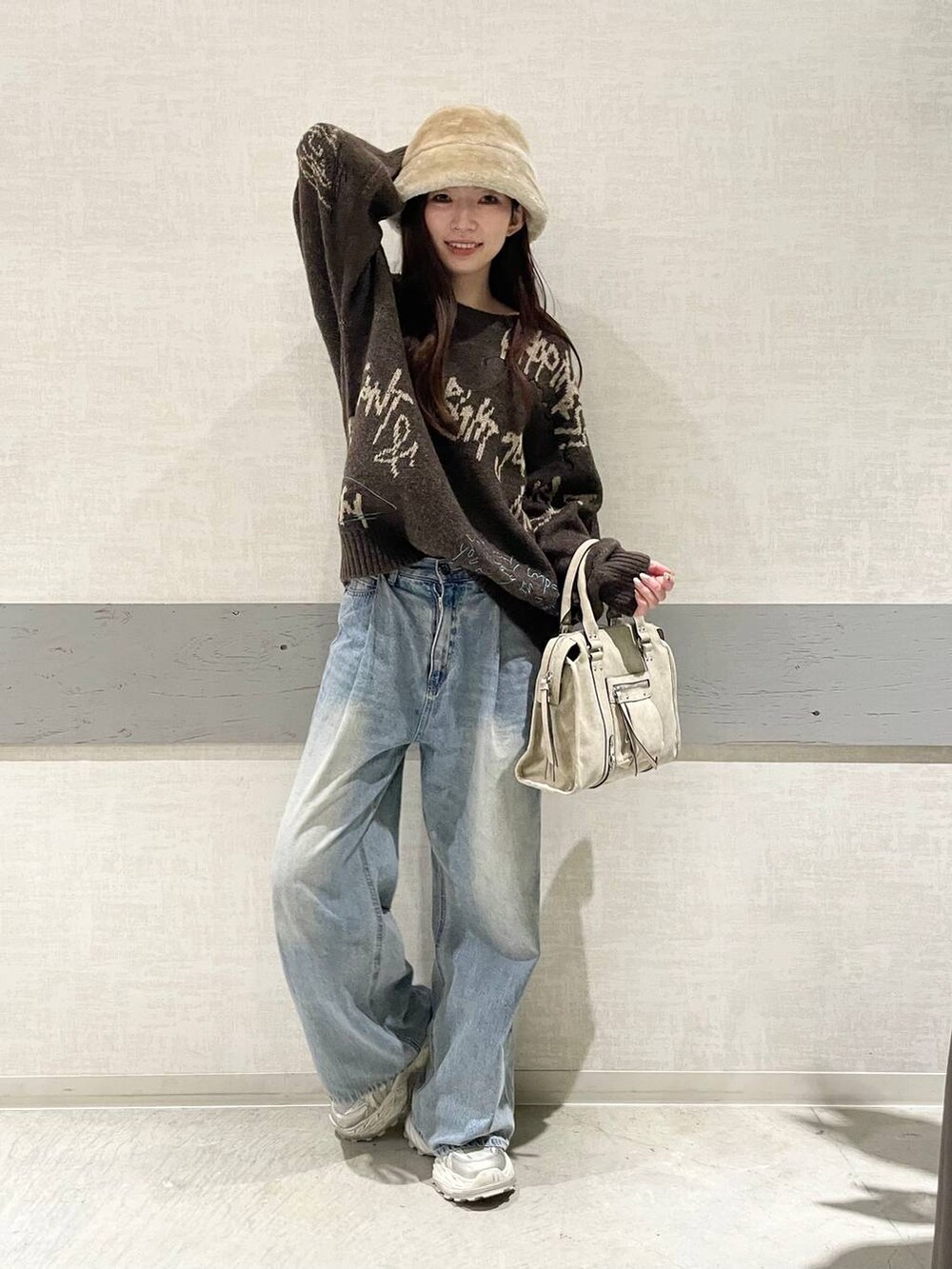 ブルー系のデニムパンツ、ホワイト系のスニーカー、ベージュ系のボストンバッグを着用したレディースの冬コーディネートの3枚目の写真