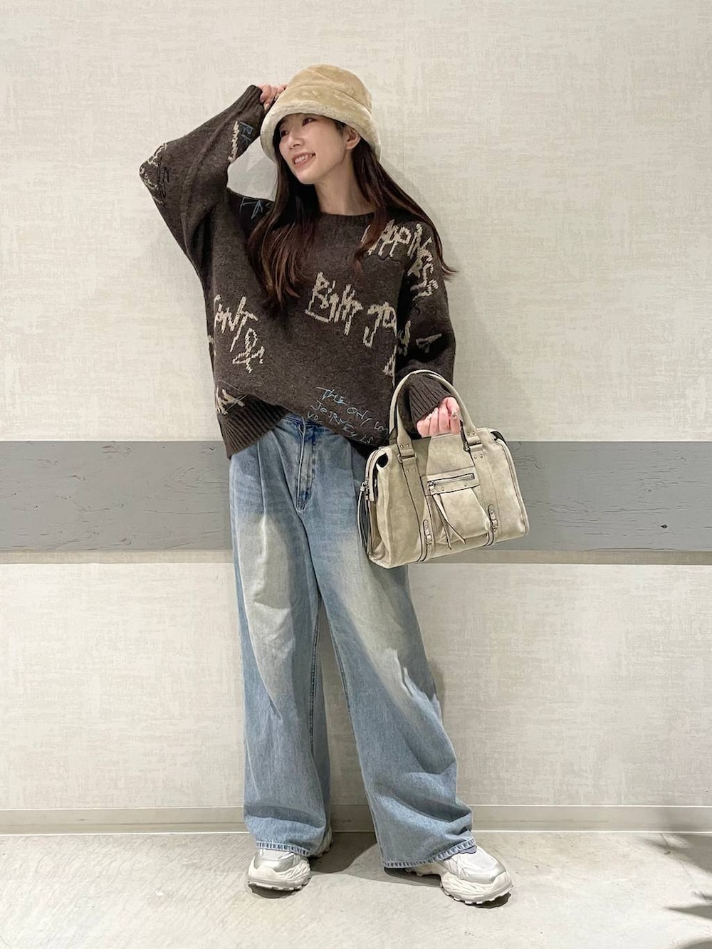 ブルー系のデニムパンツ、ホワイト系のスニーカー、ベージュ系のボストンバッグを着用したレディースの冬コーディネートの5枚目の写真