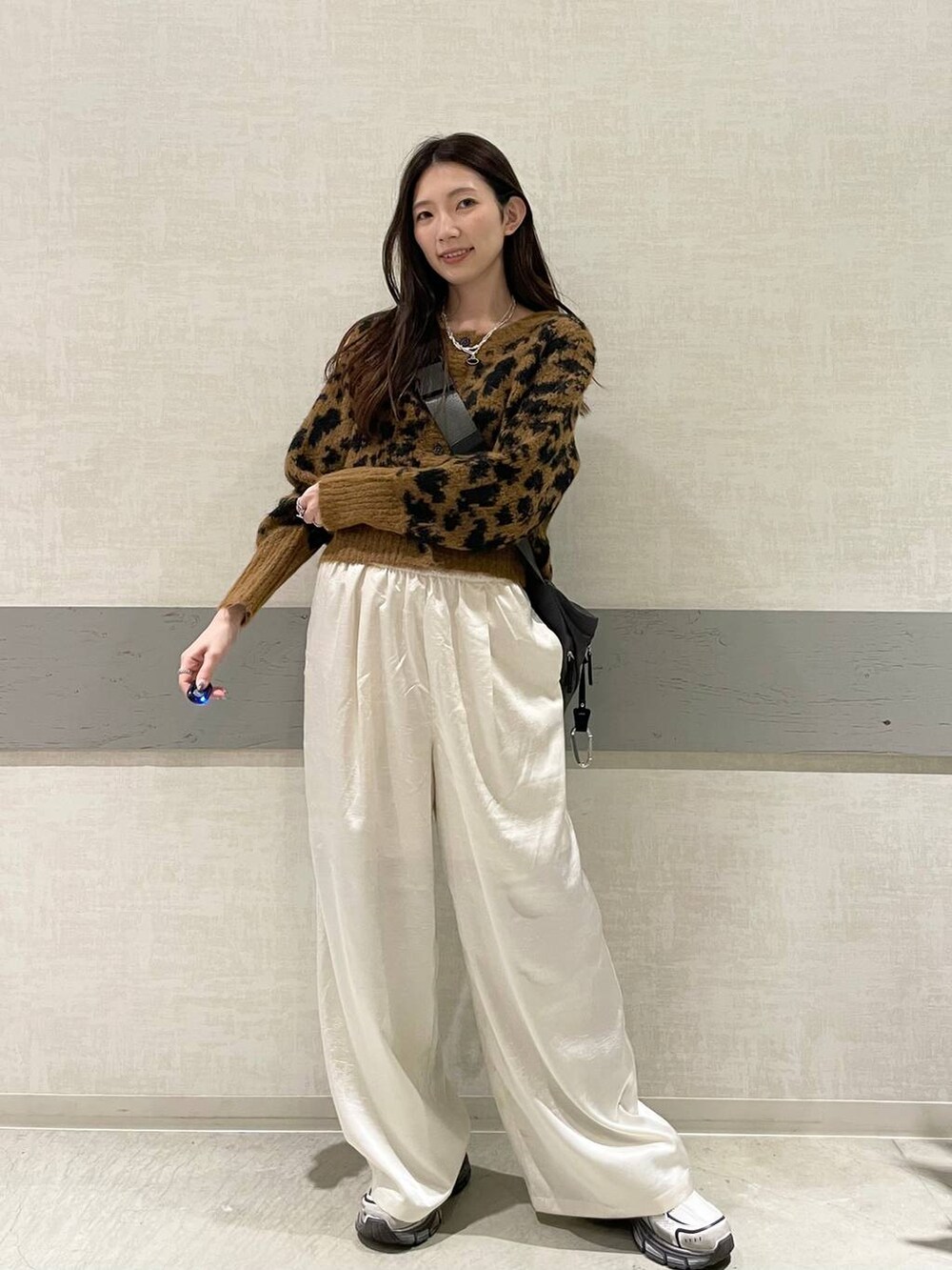 グレー系のショルダーバッグ、ホワイト系のスニーカー、ブラウン系のカーディガン/ボレロを着用したレディースの冬コーディネートの3枚目の写真