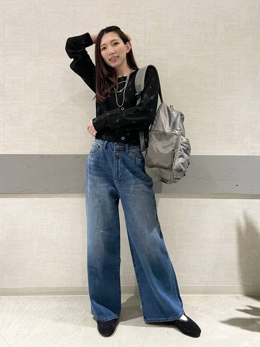 ブラック系のパンプス、グリーン系のバックパック/リュック、ブルー系のデニムパンツを着用したレディースの冬コーディネートの2枚目の写真