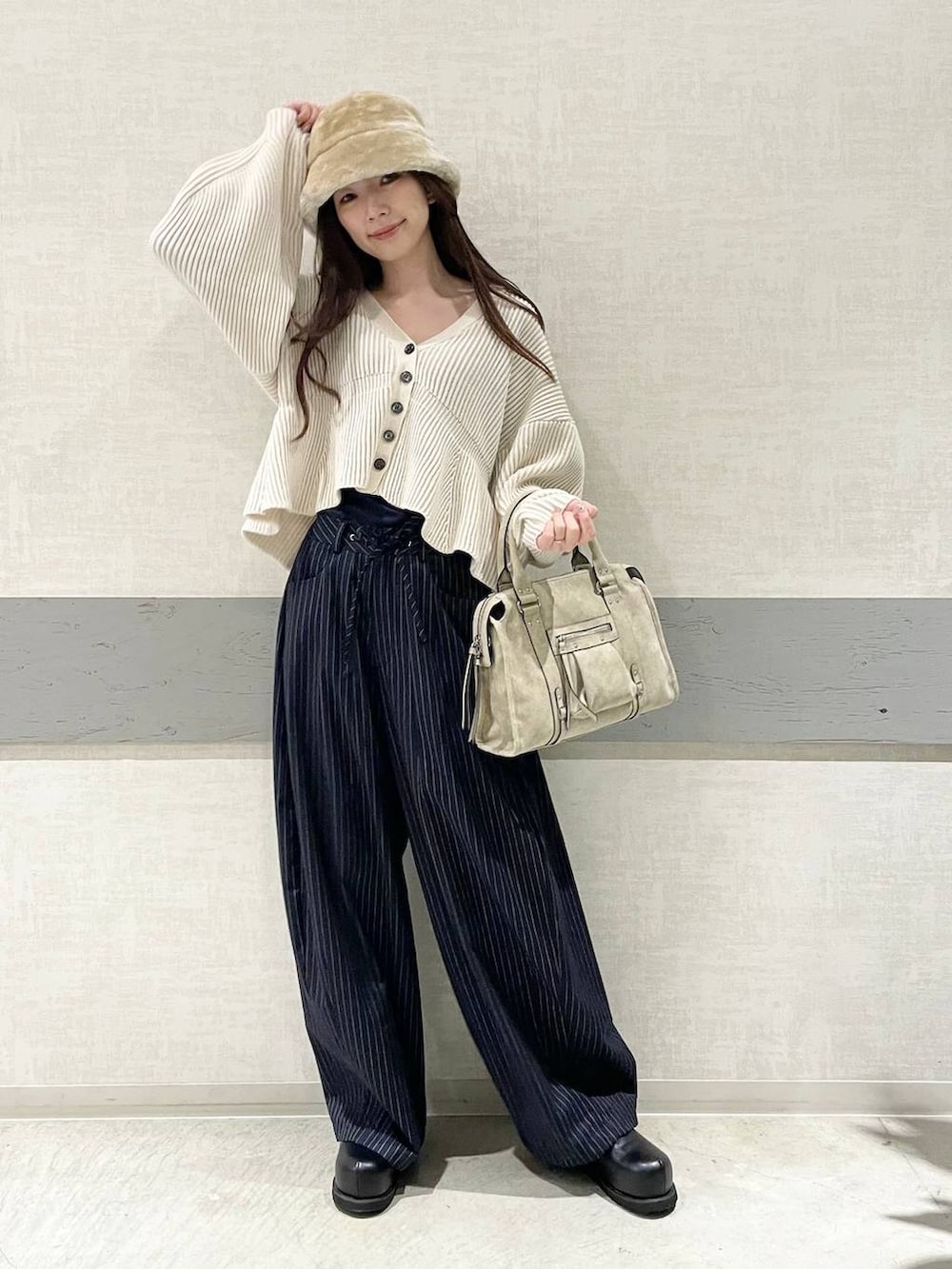 ベージュ系のボストンバッグ、ブルー系のスラックス、ブラック系のその他シューズを着用したレディースの冬コーディネートの2枚目の写真