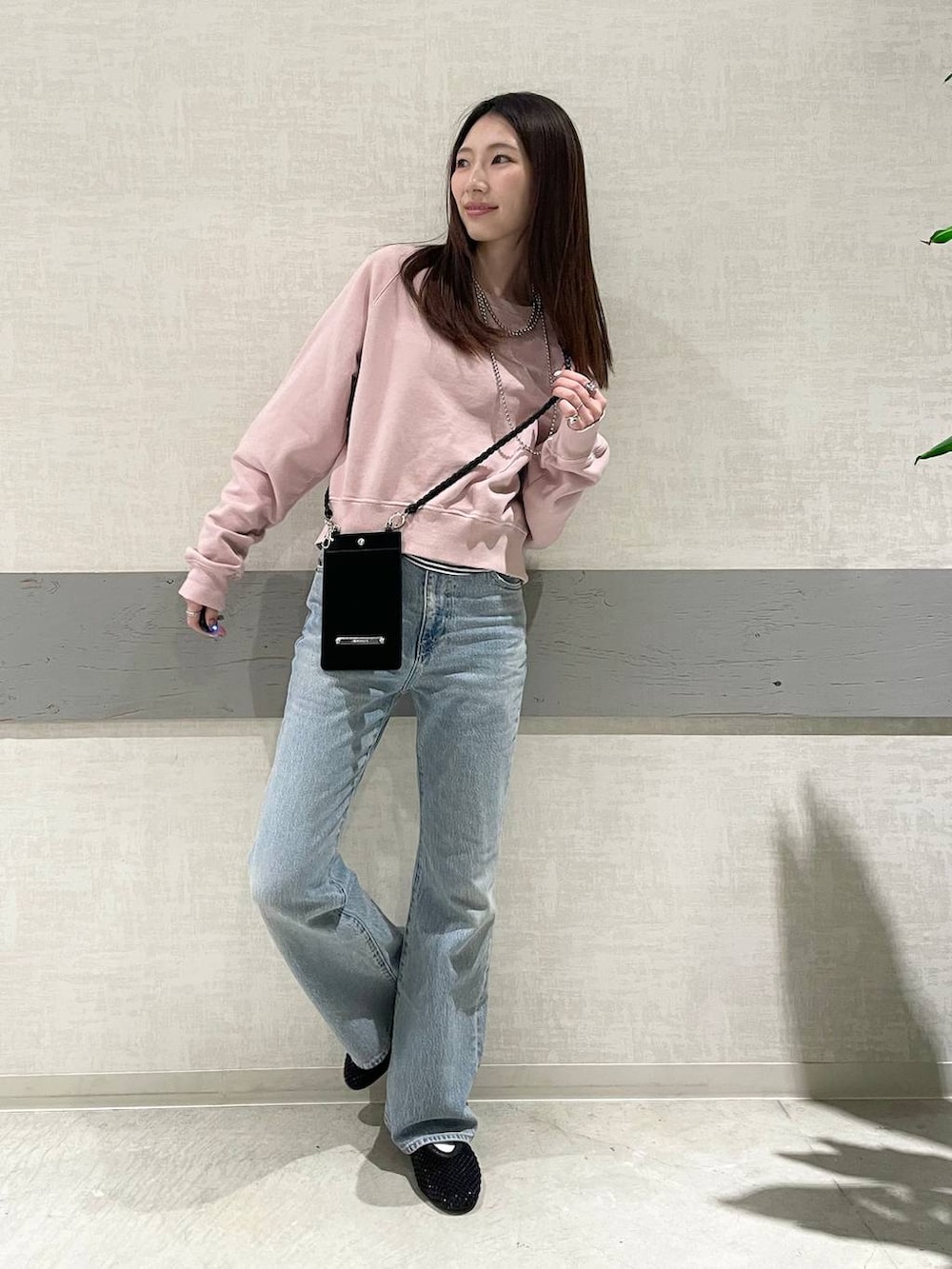 ブラック系のパンプス、ピンク系のスウェット、ブルー系のデニムパンツを着用したレディースの冬コーディネートの5枚目の写真