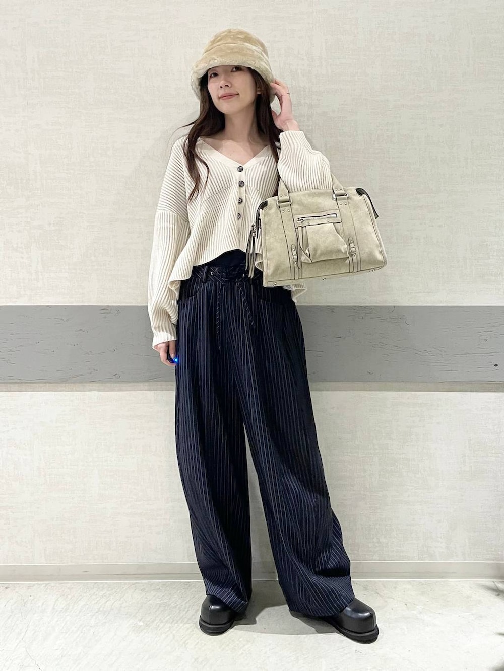 ベージュ系のボストンバッグ、ブルー系のスラックス、ブラック系のその他シューズを着用したレディースの冬コーディネートの5枚目の写真