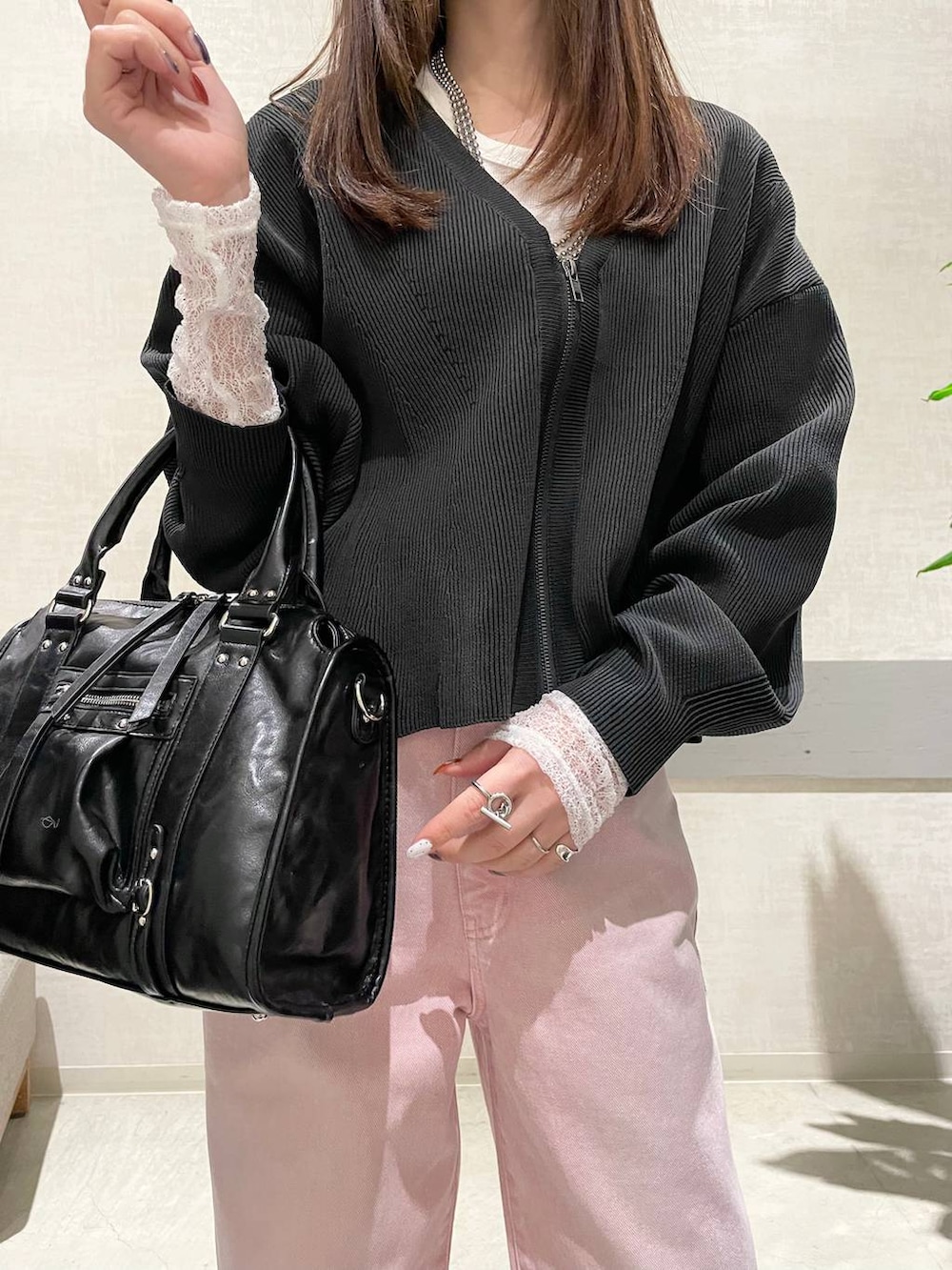 ブラック系のボストンバッグ、ブラック系のパンプス、ピンク系のデニムパンツを着用したレディースの冬コーディネートの5枚目の写真