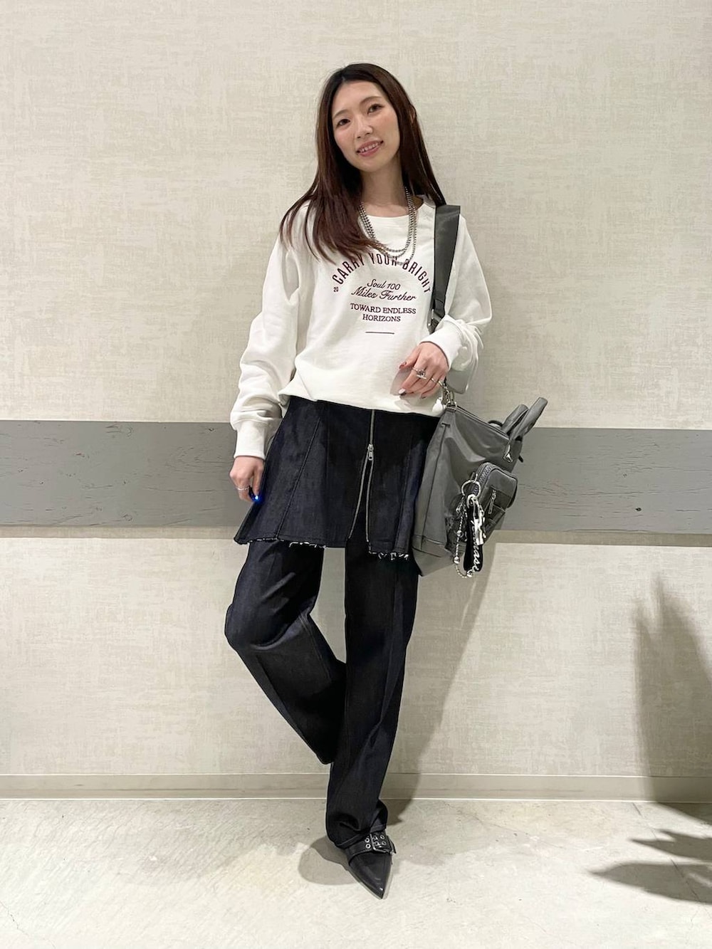 グリーン系のトートバッグ、ブラック系のパンプス、ブルー系のデニムパンツを着用したレディースの冬コーディネートの2枚目の写真