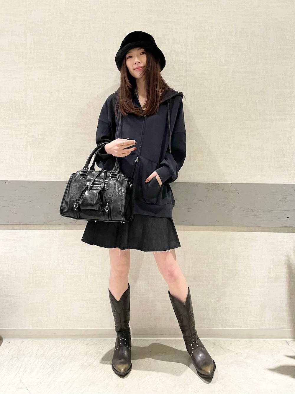 ブラック系のボストンバッグ、ブラック系のブーツ、ブルー系のパーカーを着用したレディースの冬コーディネートの5枚目の写真