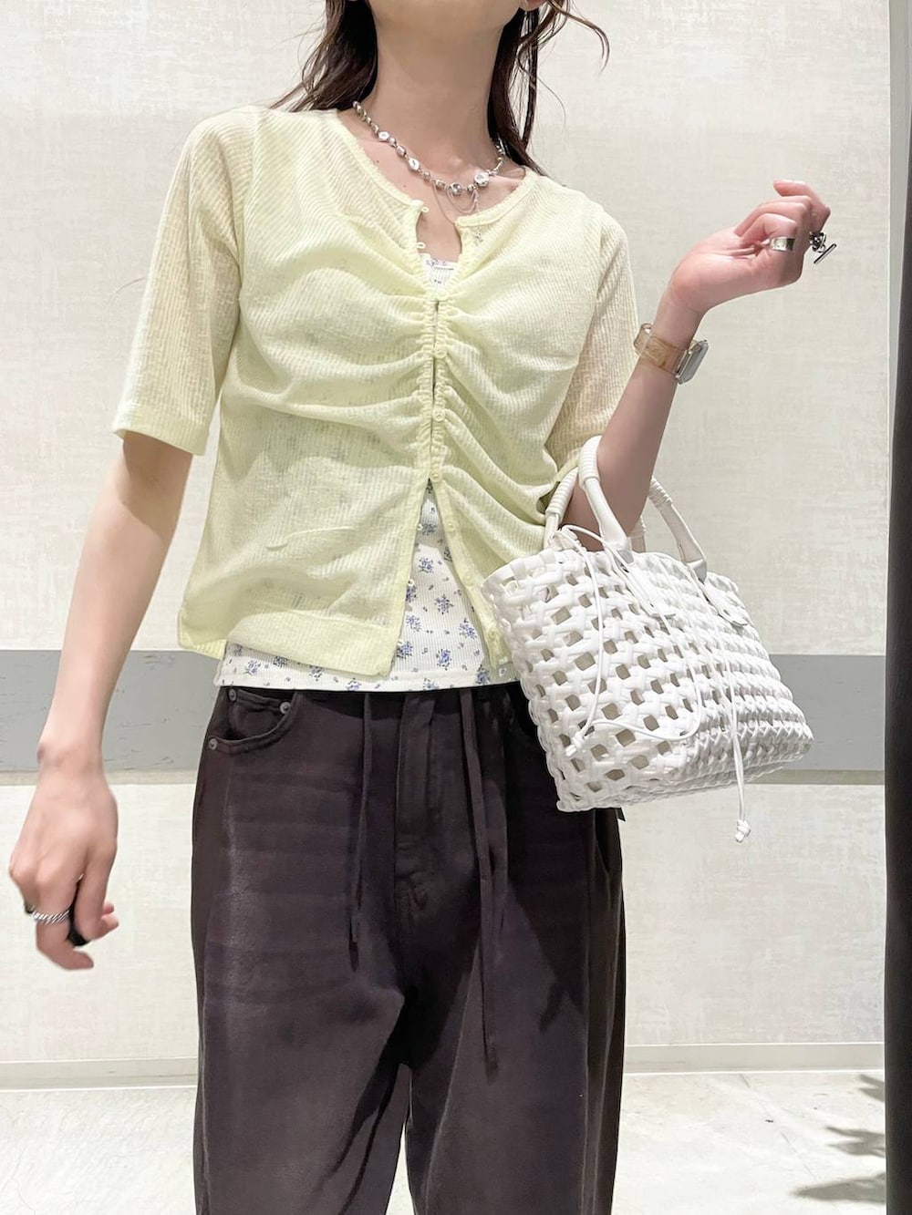 イエロー系のカーディガン/ボレロ、ブラウン系のデニムパンツ、ホワイト系のハンドバッグを着用したレディースの夏コーディネートの3枚目の写真