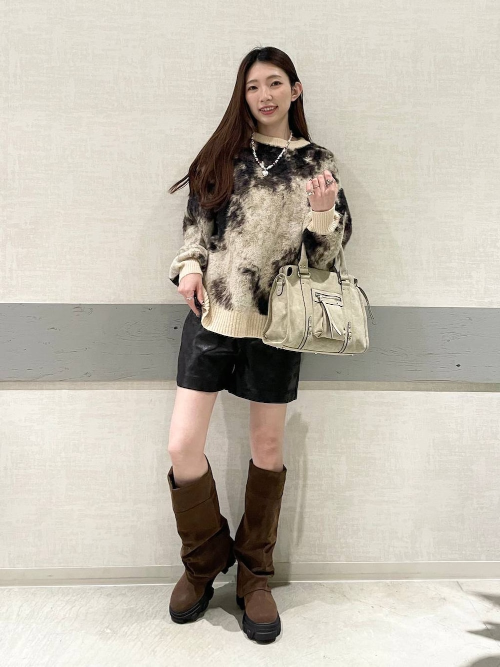 ブラウン系のニット/セーター、ベージュ系のボストンバッグ、ブラウン系のブーツを着用したレディースの秋コーディネートの6枚目の写真