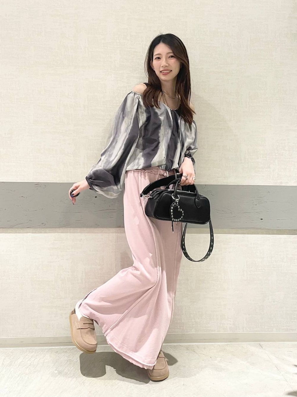 ブラック系のボストンバッグ、ベージュ系のローファー、ピンク系のスカートを着用したレディースの春コーディネートの3枚目の写真