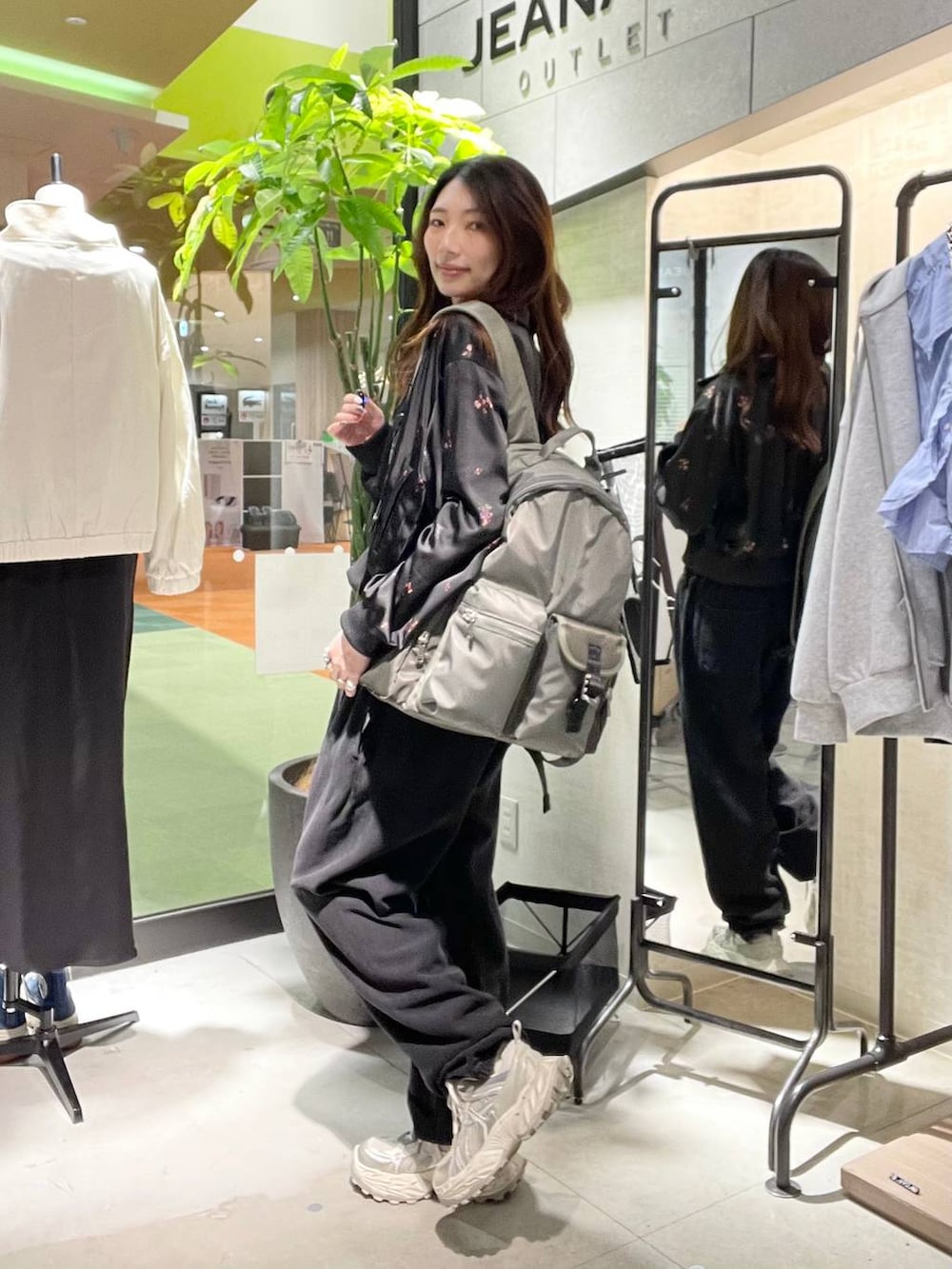 シルバー系のスニーカー、ブラック系のスウェットパンツ、グリーン系のバックパック/リュックを着用したレディースの春コーディネートの2枚目の写真