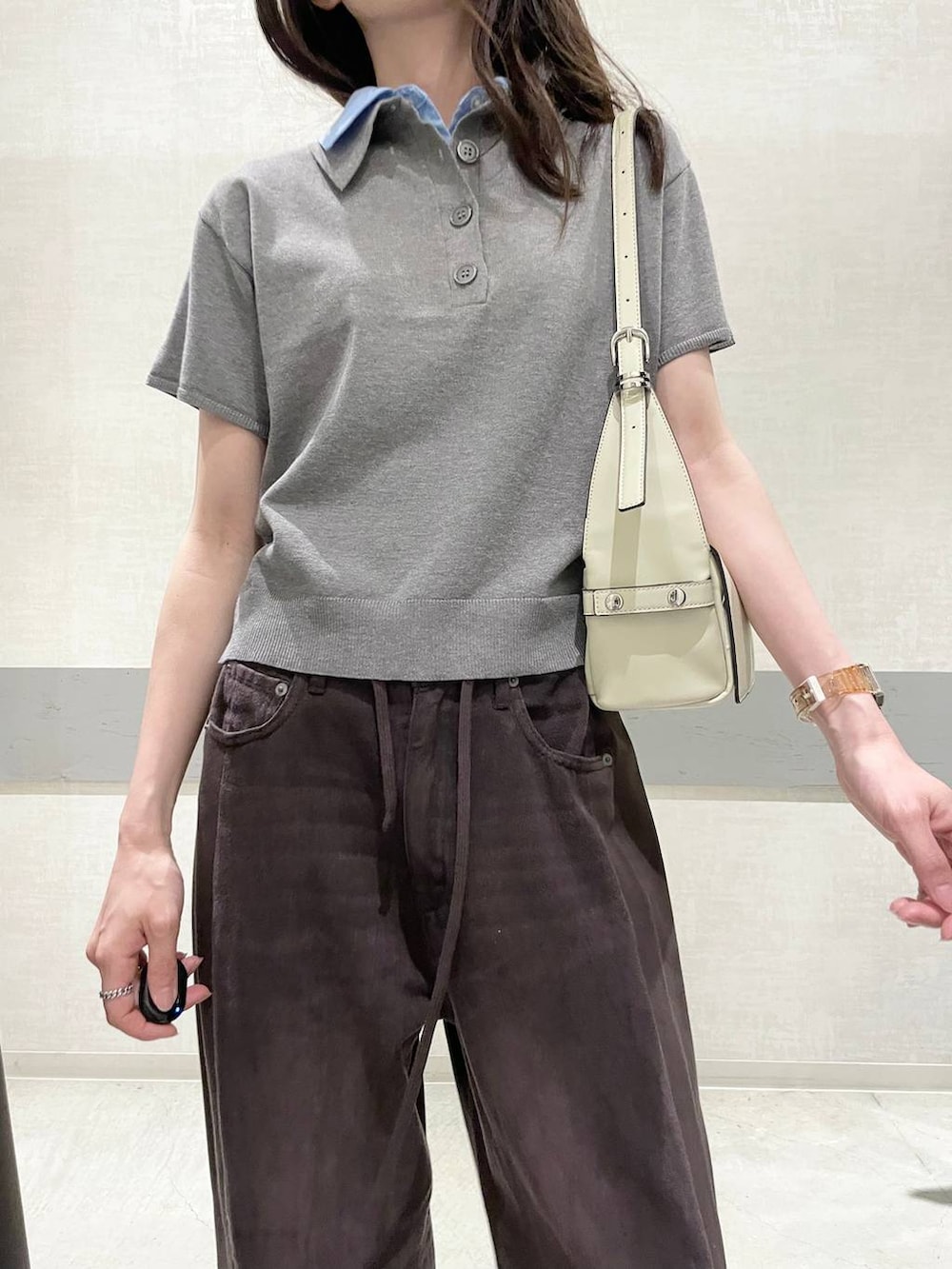 ブラウン系のデニムパンツ、ホワイト系のショルダーバッグ、グレー系のポロシャツを着用したレディースの夏コーディネートの4枚目の写真