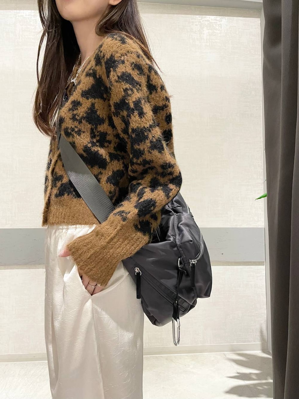 グレー系のショルダーバッグ、ホワイト系のスニーカー、ブラウン系のカーディガン/ボレロを着用したレディースの冬コーディネートの4枚目の写真