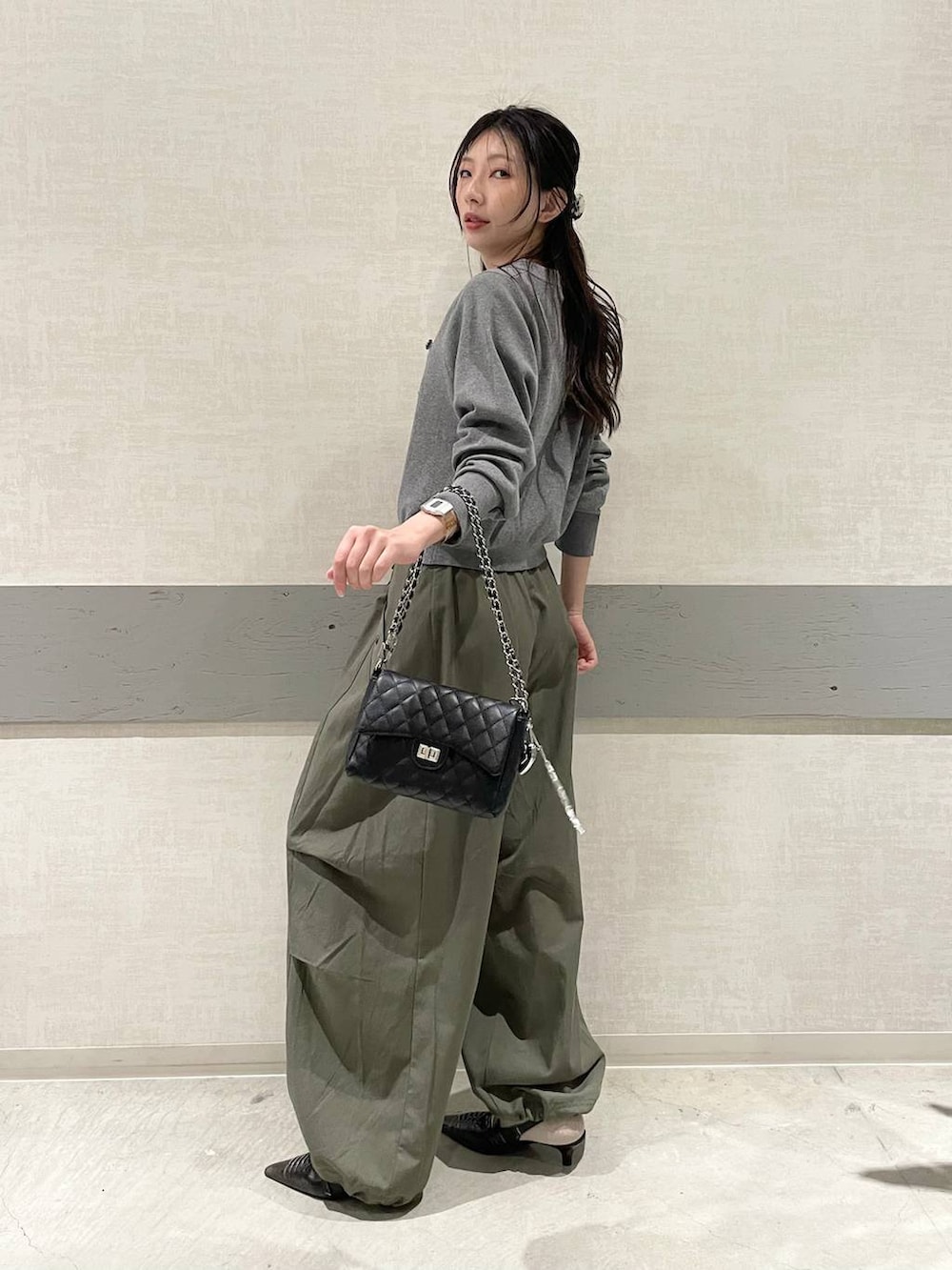 グレー系のカーディガン/ボレロ、ブラック系のパンプス、グリーン系のその他パンツを着用したレディースの秋コーディネートの2枚目の写真