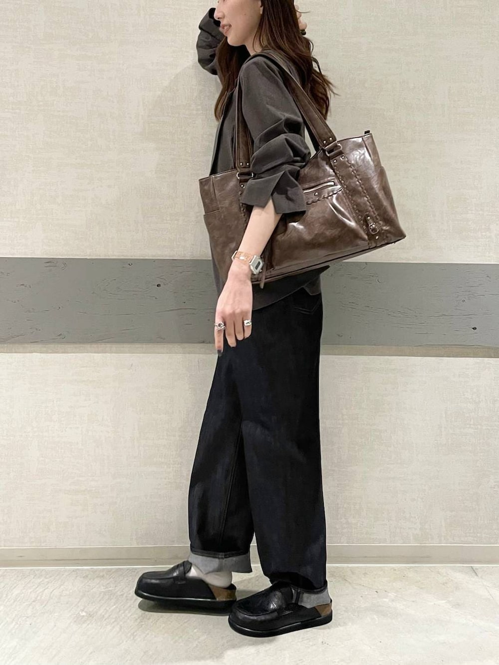 ブラック系のローファー、ブラウン系のトートバッグ、ブルー系のデニムパンツを着用したレディースの春コーディネートの4枚目の写真