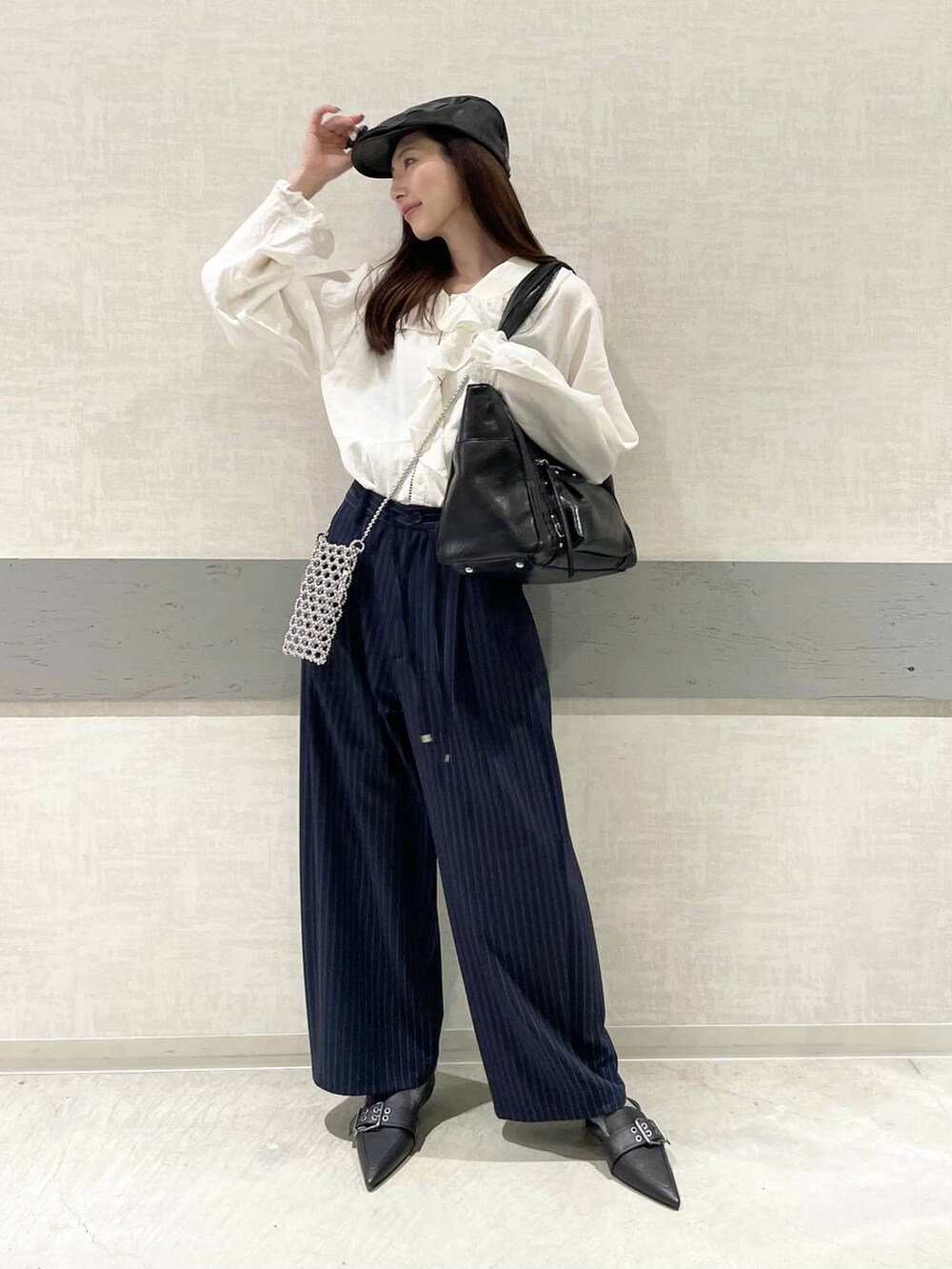 ブラック系のパンプス、ブルー系のスラックス、ブラック系のトートバッグを着用したレディースの春コーディネートの5枚目の写真