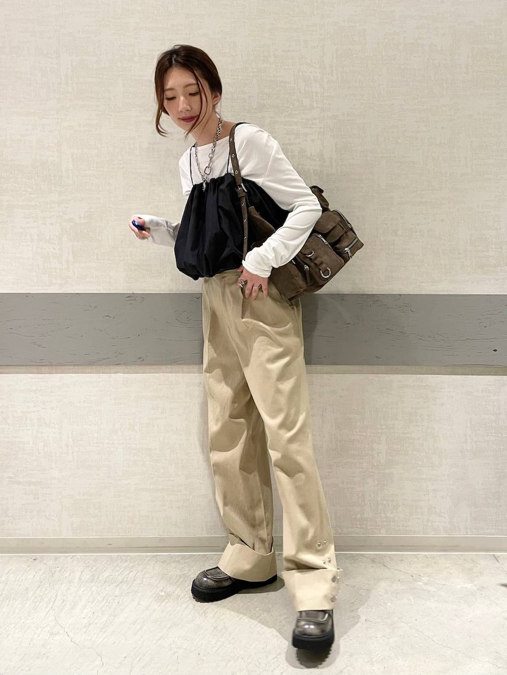 ブラウン系のショルダーバッグ、ブラック系のローファー、ベージュ系のチノパンツを着用したレディースの秋コーディネートの3枚目の写真