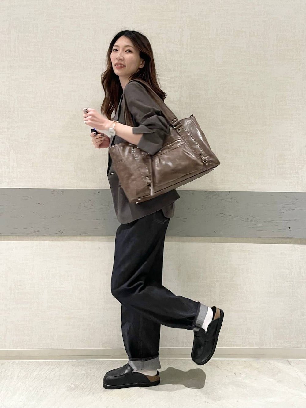 ブラック系のローファー、ブラウン系のトートバッグ、ブルー系のデニムパンツを着用したレディースの春コーディネートの3枚目の写真