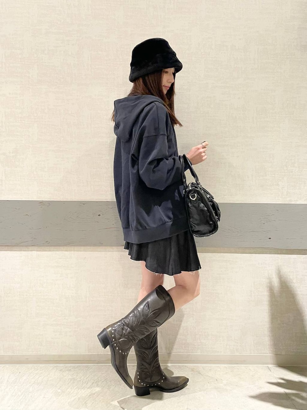 ブラック系のボストンバッグ、ブラック系のブーツ、ブルー系のパーカーを着用したレディースの冬コーディネートの4枚目の写真