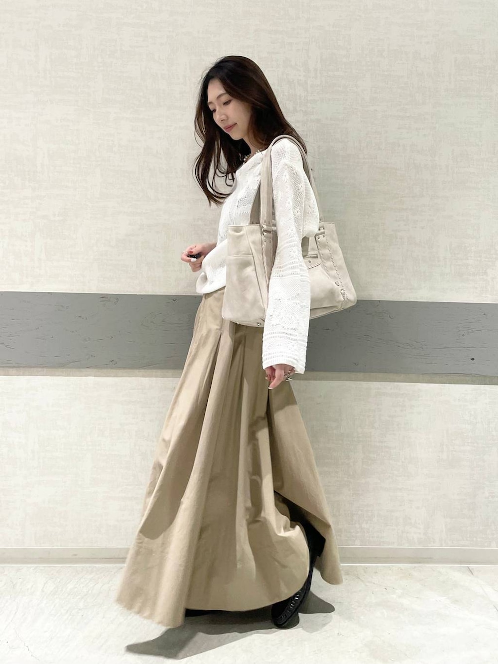 ホワイト系のトートバッグ、ベージュ系のスカート、ブラック系のローファーを着用したレディースの春コーディネートの3枚目の写真