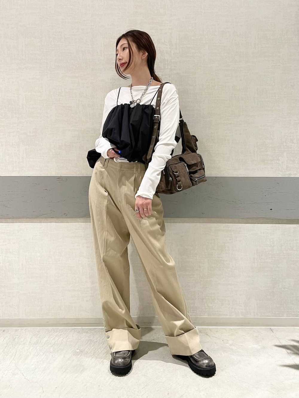 ブラウン系のショルダーバッグ、ブラック系のローファー、ベージュ系のチノパンツを着用したレディースの秋コーディネートの4枚目の写真